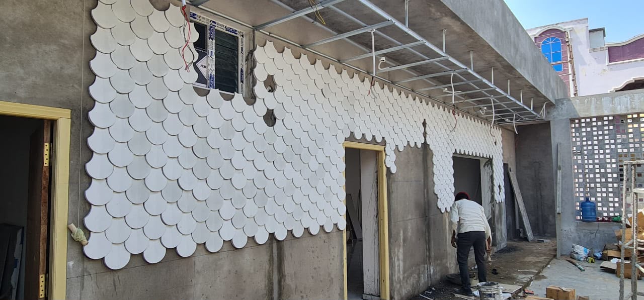 Worker installing scalloped fish-scale pattern wall panels